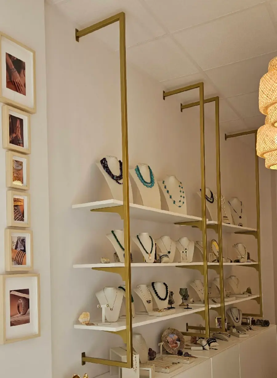Estanterías doradas con collares expuestos en Bona'Lissa